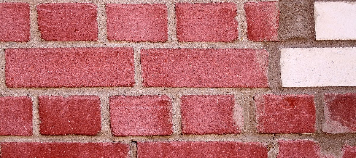 Rote Backsteinmauer mit zwei weißen Kacheln