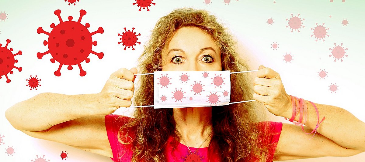 Frau vor einem Hintergrund mit roten Viren hält sich einen Mundschutz vor den Mund
