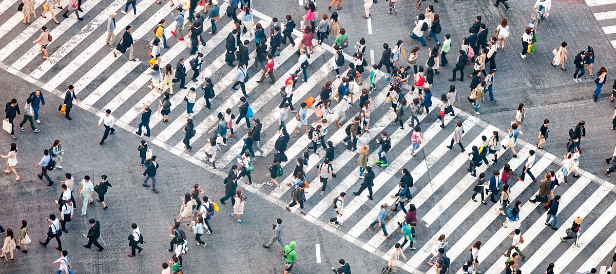 Zahlreiche Fußgänger überqueren eine große Straßenkreuzung in Tokyo