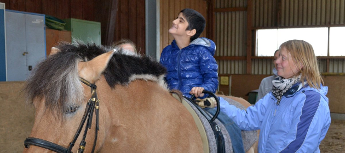 Der achtjährige Ahmed fühlt sich sichtlich wohl auf dem Rücken von Therapiepferd Janosch