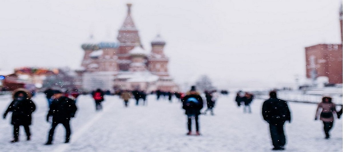 Menschen laufen über den verschneiten Roten Platz mit der St. Basilius Kathedrale im Hintergrund
