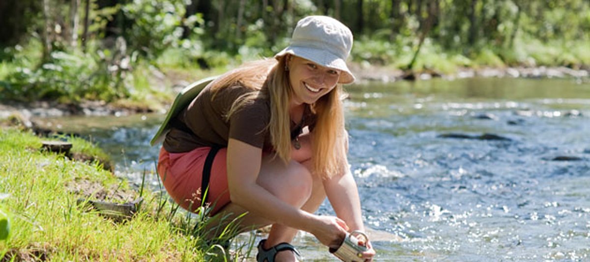 Eine junge Frau spült ihre Tasche im Fluss