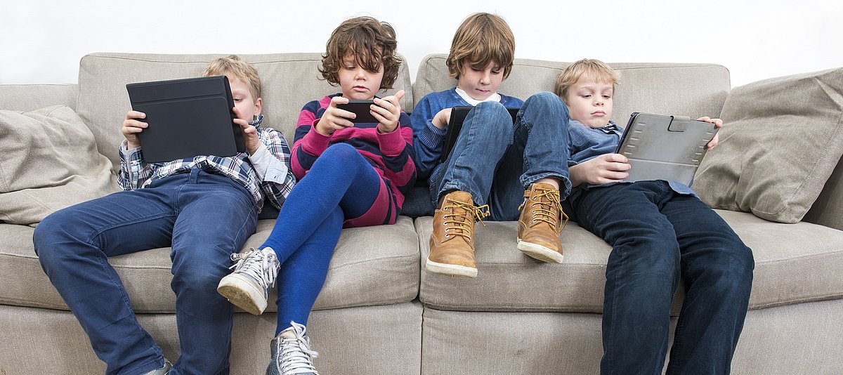 Jungs auf Sofa mit Tablets und Smartphones