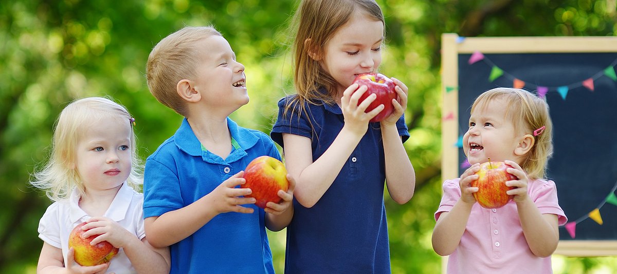 Kinder essen Äpfel und lachen