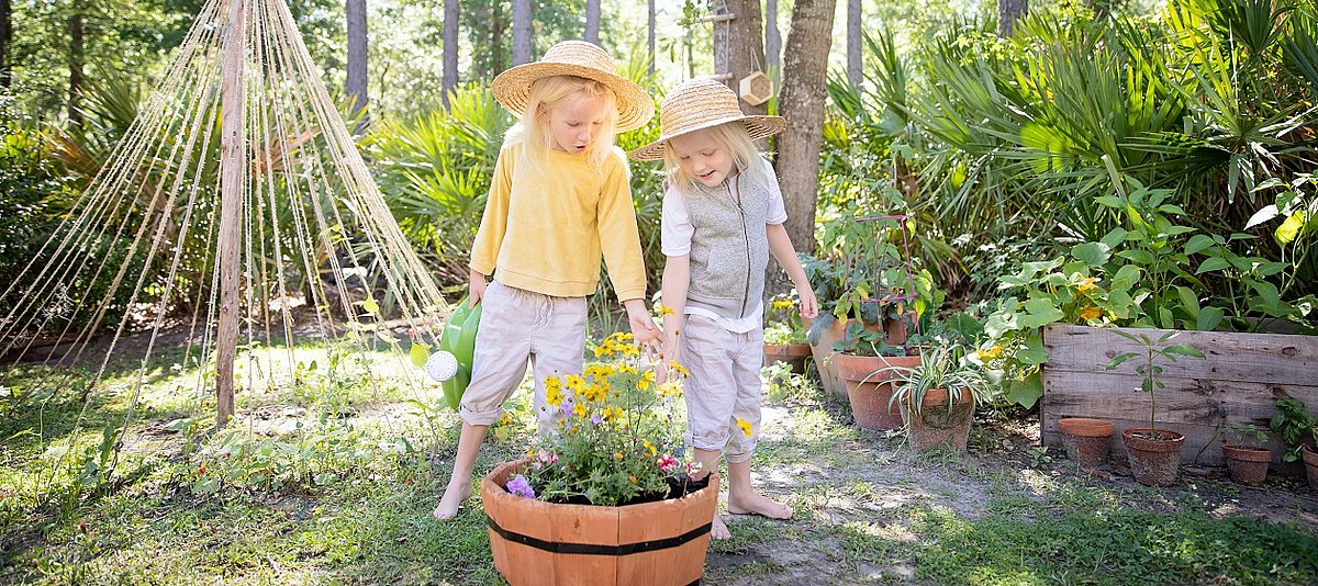 Zwei Kinder gießen Blumen in einem Garten
