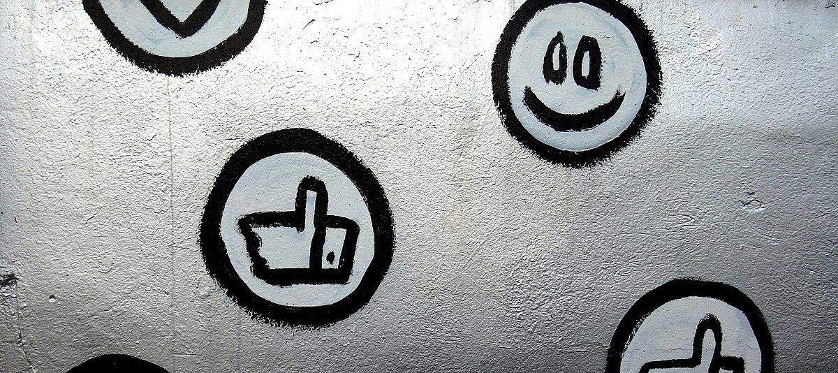 Auf eine Wand sind verschiedene Emojis gezeichnet, unter anderem ein Smiley und ein Like-Button