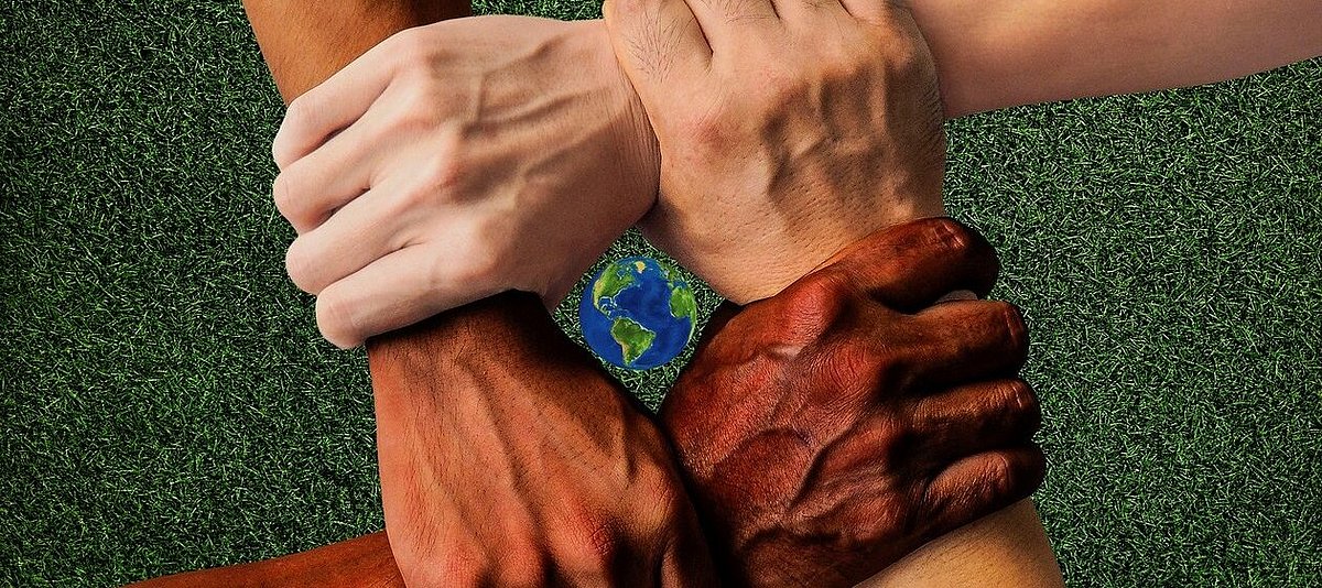 Vier Hände verschiedener Hautfarbe fassen sich am Handgelenk