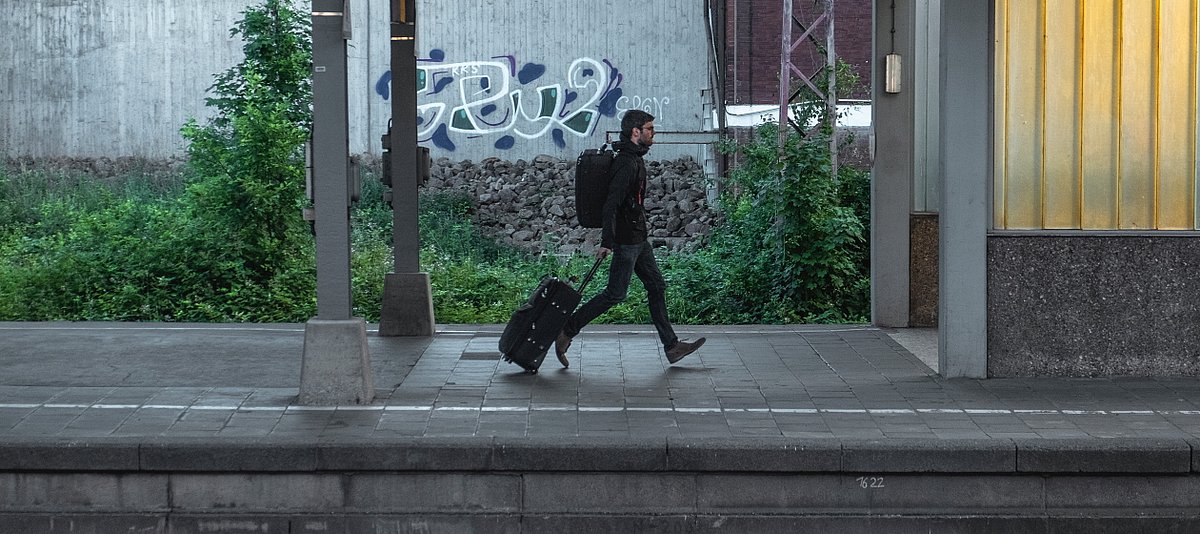 Ein Mann mit einem Koffer und einem Rucksack an einer S-Bahn-Station