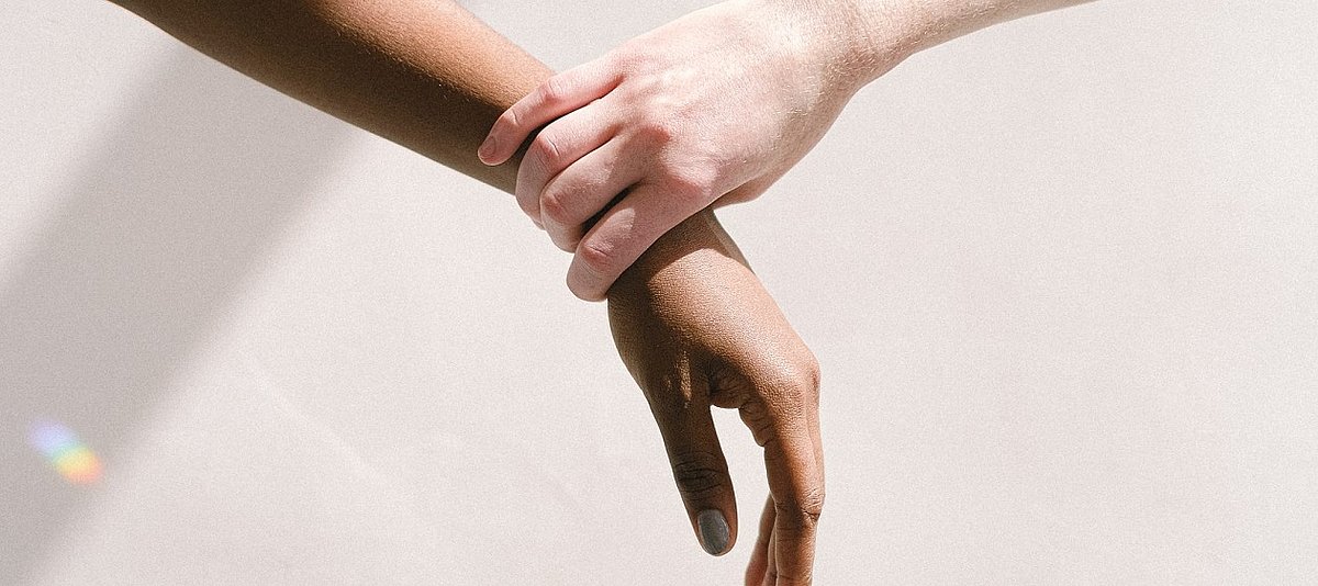 Eine Hand hält eine andere Person am Arm