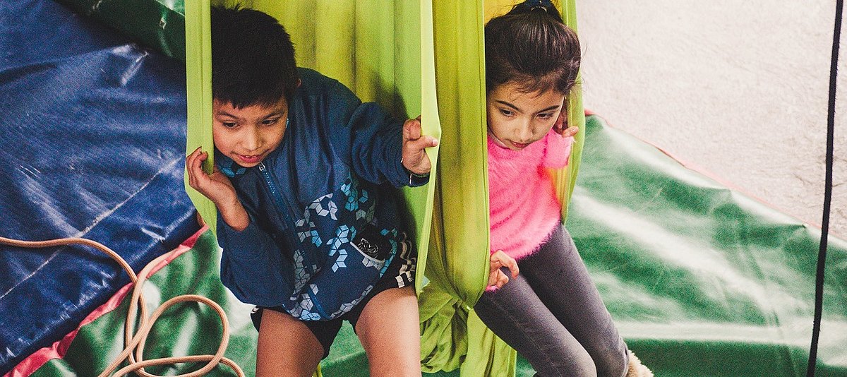 Zwei Kinder sitzen in hängenden Tüchern