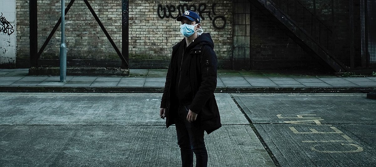 Jugendlicher mit Atemschutzmaske auf einer leeren Straße