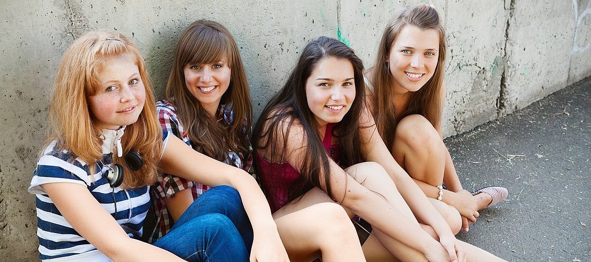 Vier Mädchen sitzen zusammen und lachen.