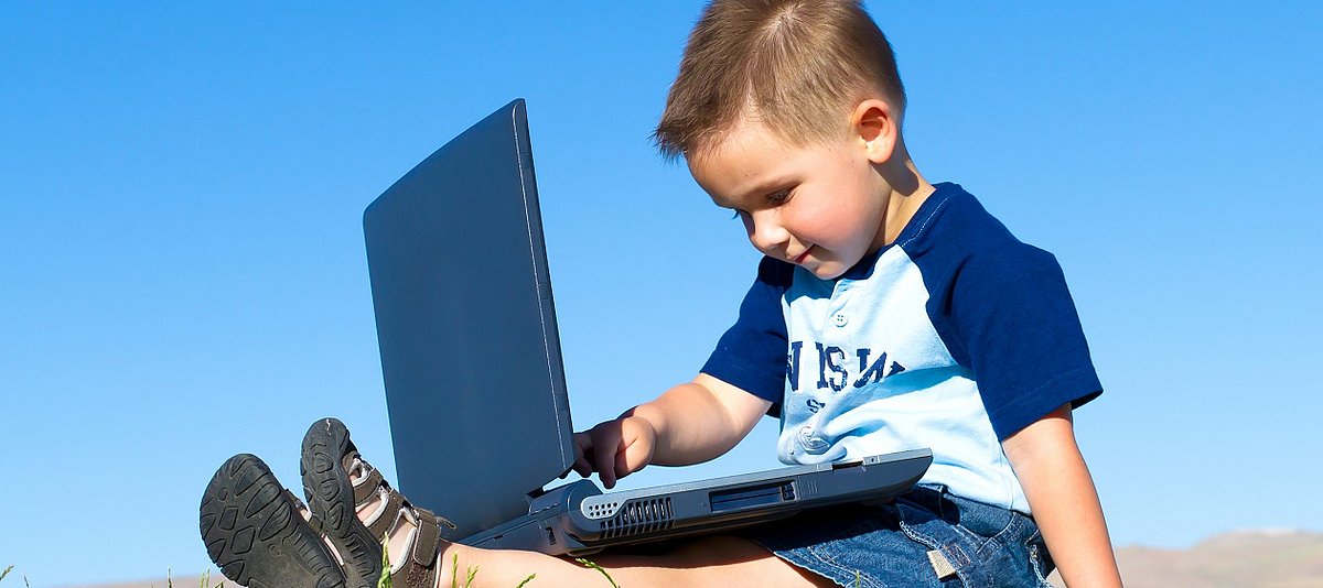 Ein Junge sitzt am Computer und beschäftigt sich damit.