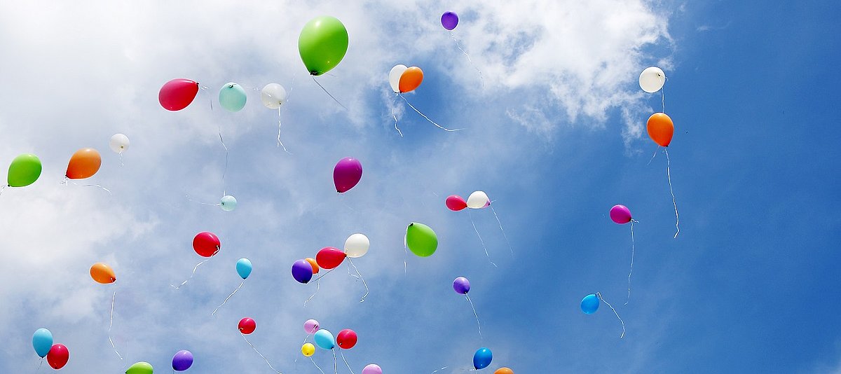 Bunte Luftballons steigen in blauen Himmel