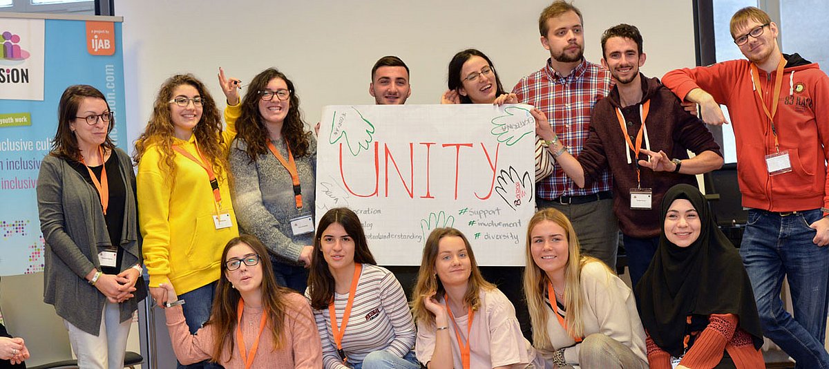 Teilnehmende des Barcamp halten ein Schild mit der Aufschrift "Unity"