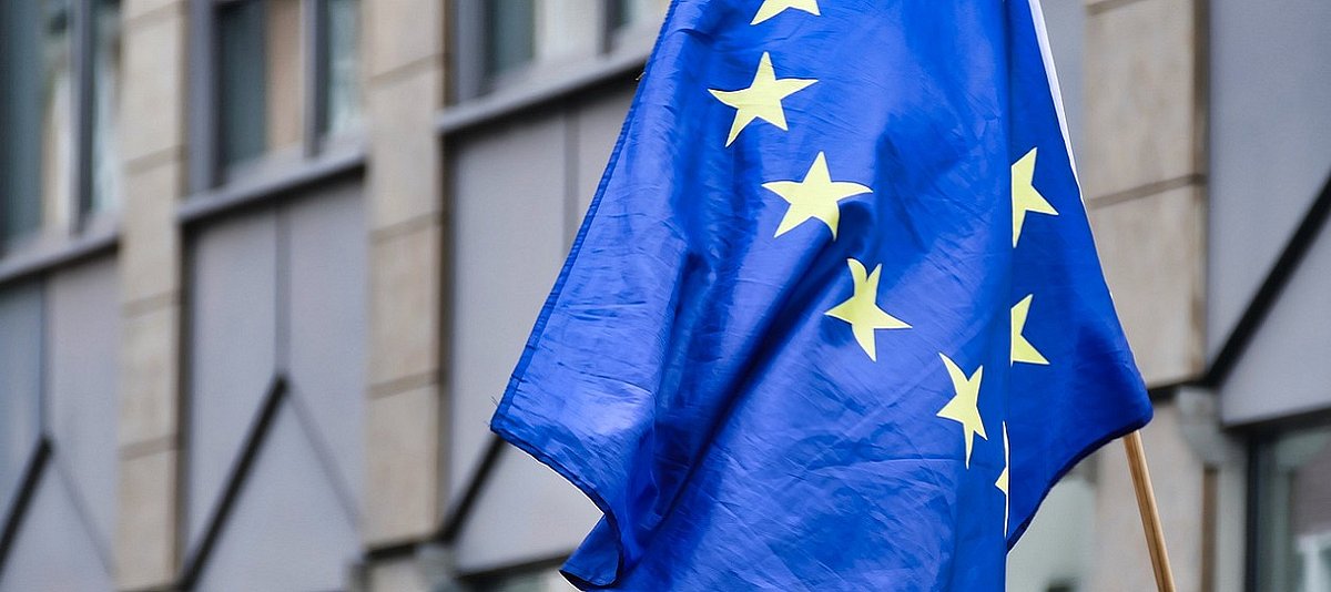 Das Bild zeigt eine europäische Fahne vor einem Gebäude.