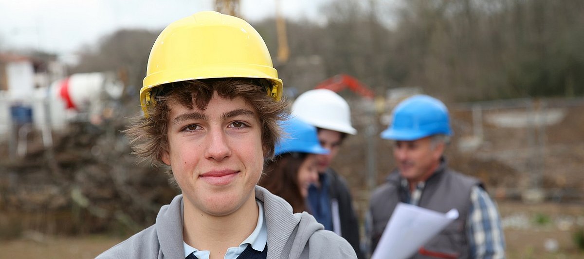Ein junger Mann ist als Auszubildender auf einer Baustelle.