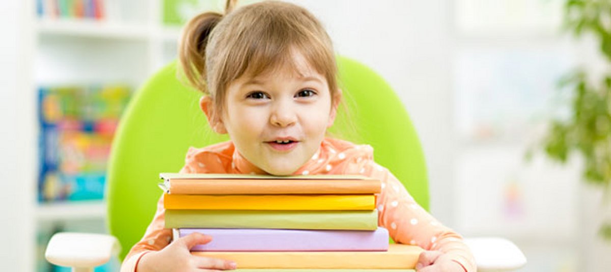 Ein Mädchen mit einem Stapel bunter Bücher