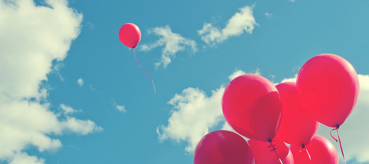 Rote Luftballons fliegen am Himmel