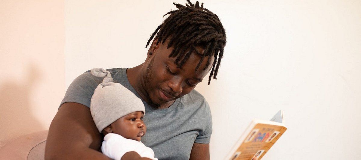 Ein Vater liest einem Baby aus einem Buch vor