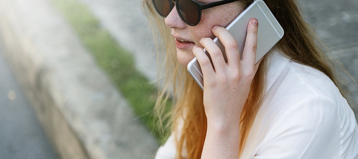 Jugendliche mit Sonnenbrille telefoniert mit ihrem Smartphone