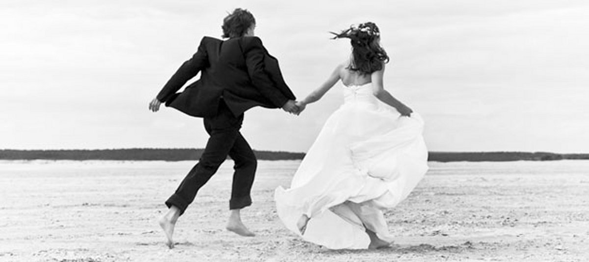 Ein Hochzeitspaar läuft über den Strand