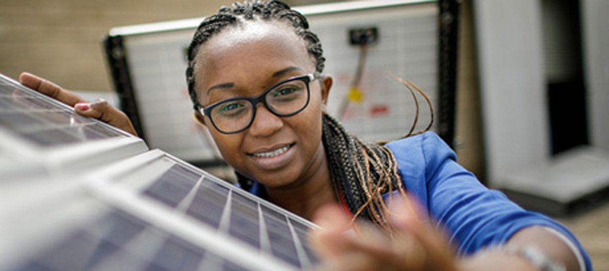 Eine junge Person arbeitet an einer Solaranlage