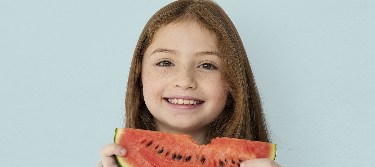 Ein lächlendes Mädchen isst eine Wassermelone