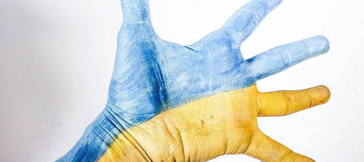 Eine ausgestreckte Hand in den ukrainischen Nationalfarben blau und gelb 