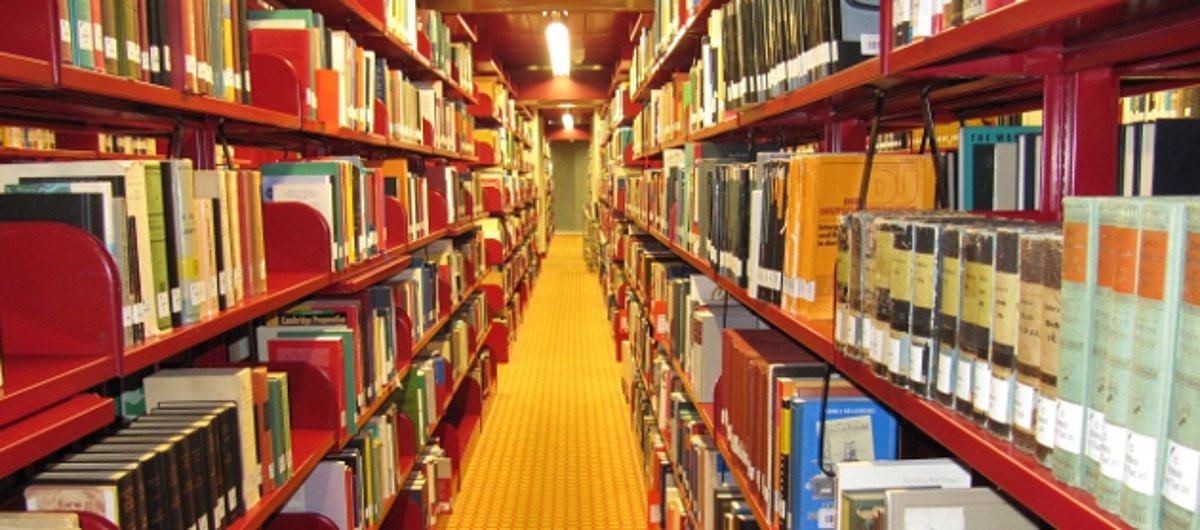 ein Gang einer Bibliothek mit langen Bücherregalen
