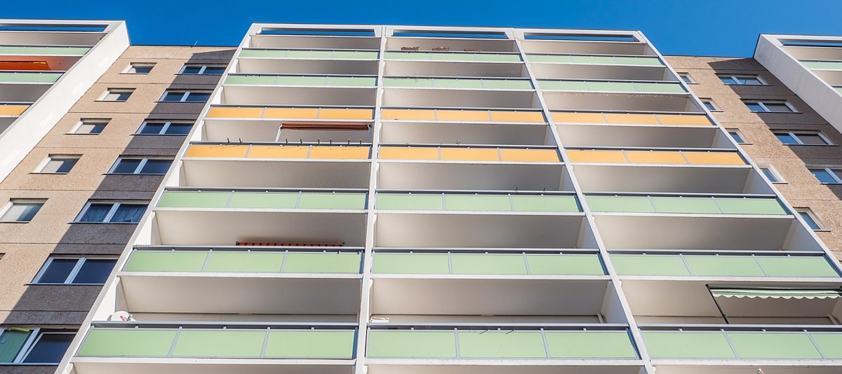Blick an einem Plattenbau mit verschieden farbigen Balkonen hoch