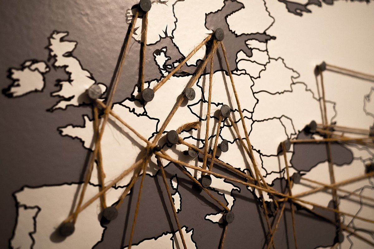 Eine Europakarte ist mit Pins markiert, die mit Schnüren verbunden sind.