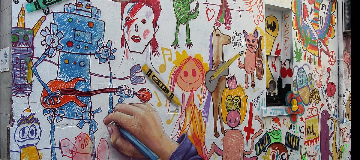Buntes Graffiti zeigt eine Kinderhand, die mit Wachsmalstiften ein buntes Bild malt.