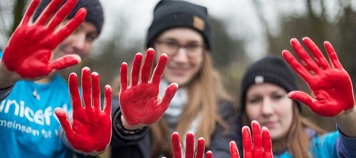 Jugendliche setzen mit roten Händen ein Zeichen gegen den Einsatz von Kindersoldaten 