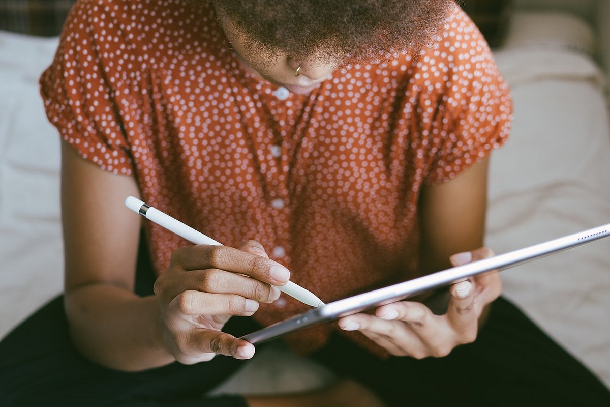Jugendliche schreibt mit einem Touchscreen-Stift auf einem Tablet.