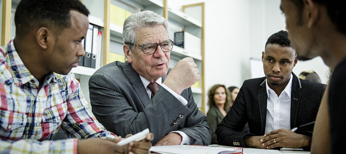 Bundespräsident Joachim Gauck sitzt mit drei jugendlichen Schwarzafrikanern an einem Tisch