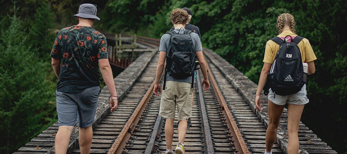 Vier Jugendliche spazieren auf alten Bahngleisen