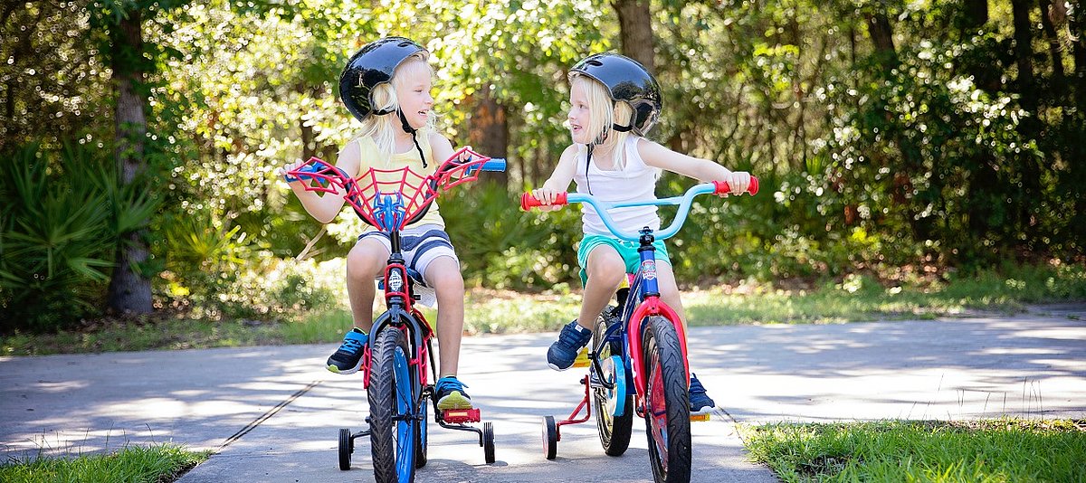 Zwei Mädchen fahren auf Fahrrädern mit Stützrädern