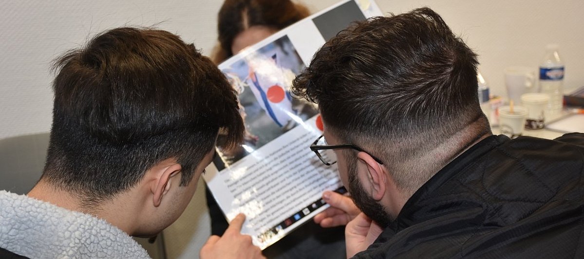 Zwei Jugendliche lesen etwas, auf dem Bild zum Text ist die Flagge Israels zu sehen