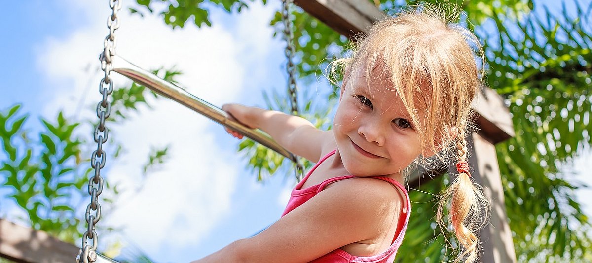 Ein Mädchen hält sich an einer Leiter auf einem Spielplatz fest