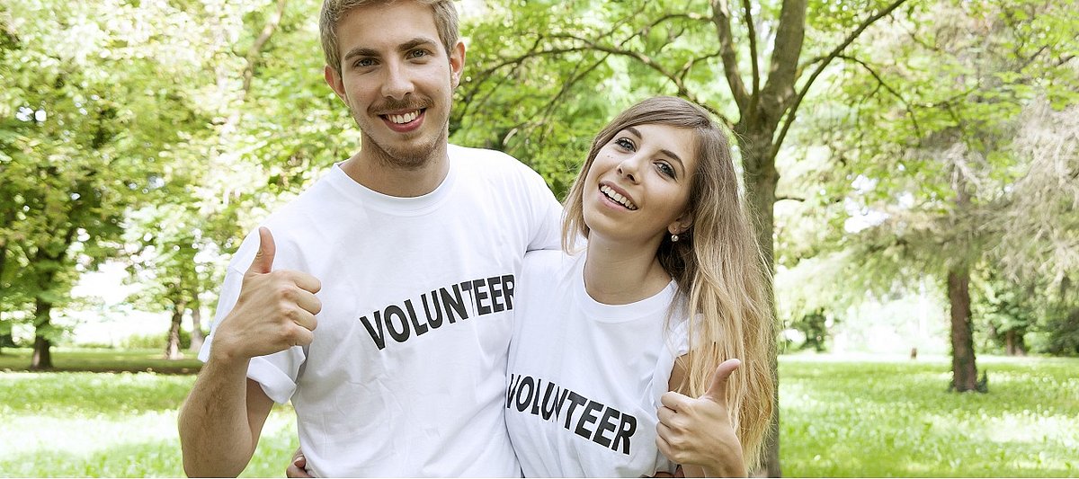 Zwei Jugendliche mit T-Shirts auf denen Volunteer steht