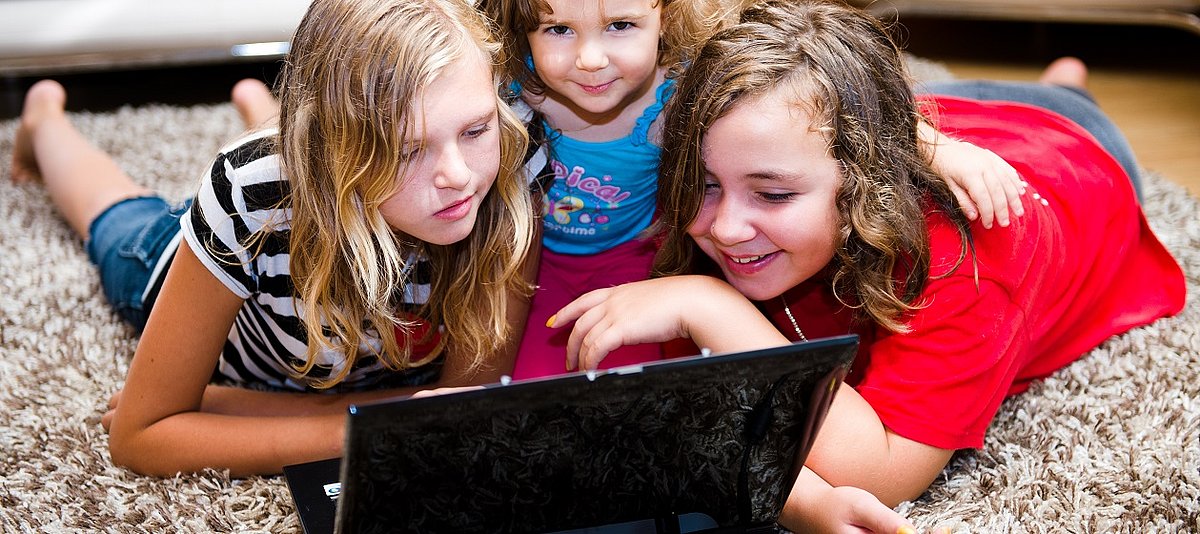 Drei Kinder sitzen vor dem Laptop