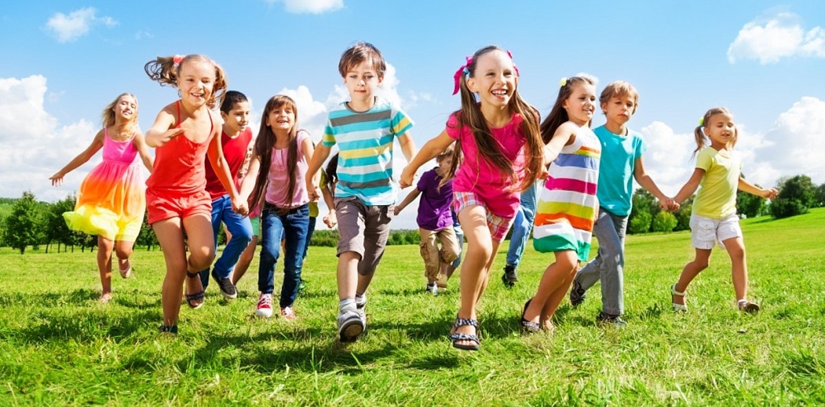 Eine Gruppe von Kindern rennt über eine Wiese