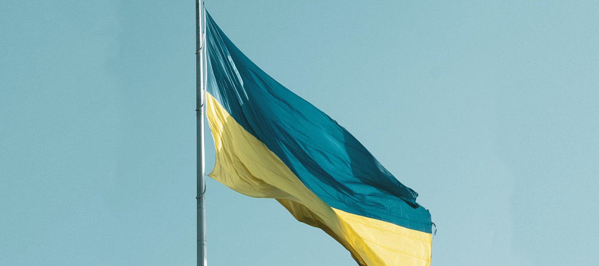 Auf dem Foto ist die Ukrainische Flagge vor blauem Himmel zu sehen.