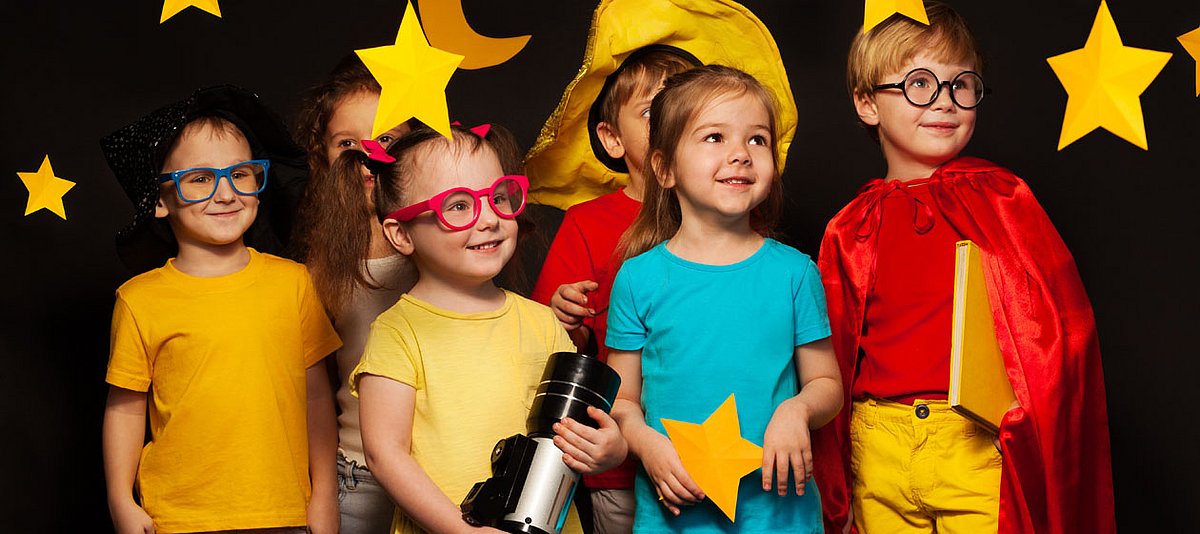Sechs Kindergartenkinder stehen auf einer Bühne mit gelben Sternen und lächeln.