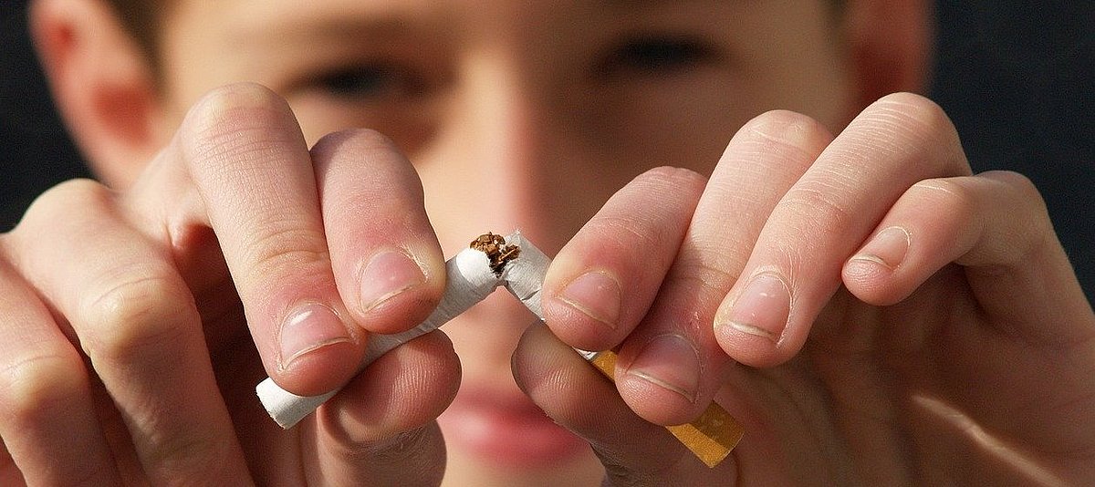 Ein Jugendlicher bricht eine Zigarette in der Mitte durch