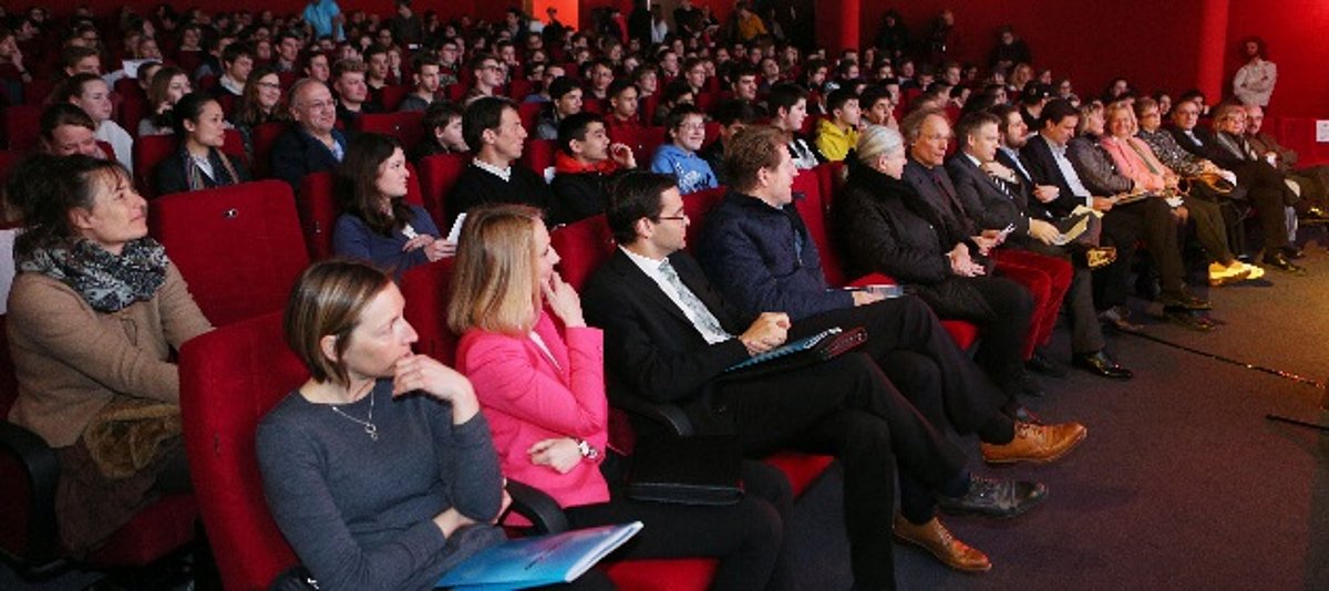 Mit Menschen besetzte Stuhlreihen in einm Kino