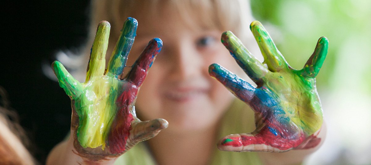 Ein Kind hat die Hände mit Fingerfarbe beschmiert