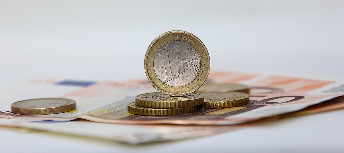 Aufgestellte Euromünzen auf Geldscheinen