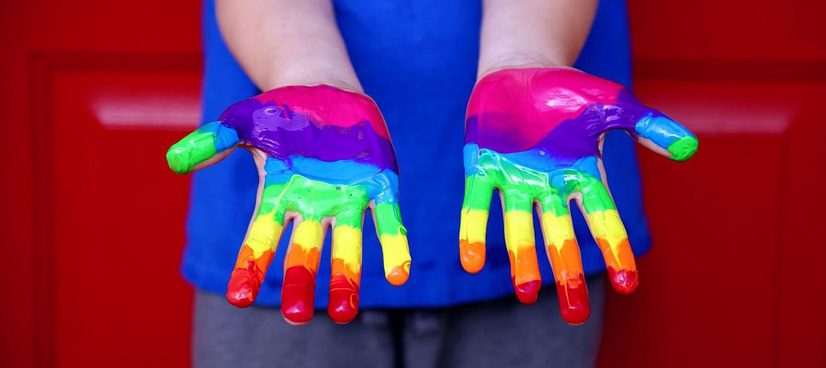 Kinderhände bemalt mit den bunten Farben des Regenbogens